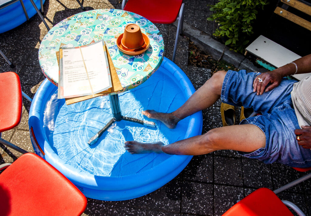 Een man zit met zijn voeten in een zwembadje op een terras aan de Nassaukade in Amsterdam op een bloedhete dag in juli tijdens de eerste hittegolf in drie jaar tijd. Het is met 35 graden nog nooit zo warm geweest in de stad. / ANP