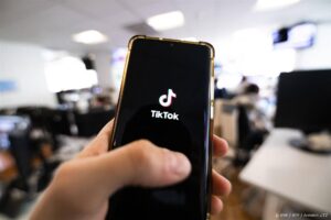 This photograph taken on April 19, 2024 shows a man holding a smartphone displaying the logo of Chinese social media platform Tiktok in an office in Paris 
Antonin UTZ / AFP